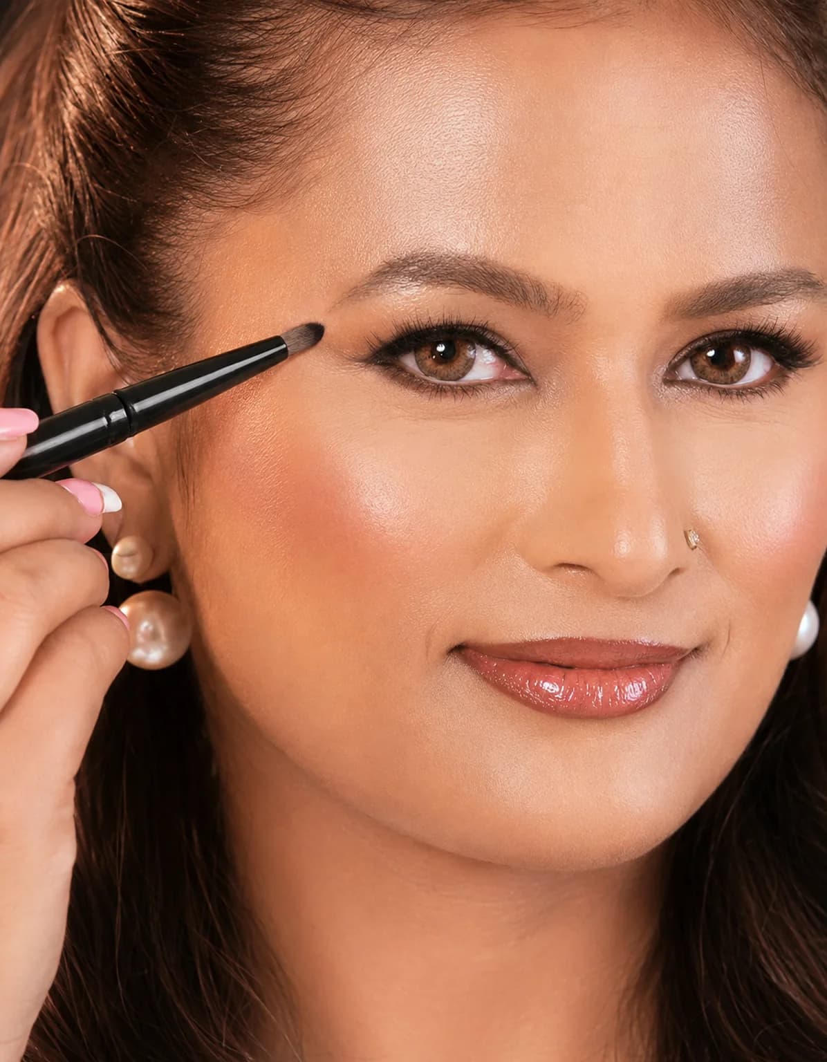A fine brush drawing precise liner along a model's lash line during a demonstration